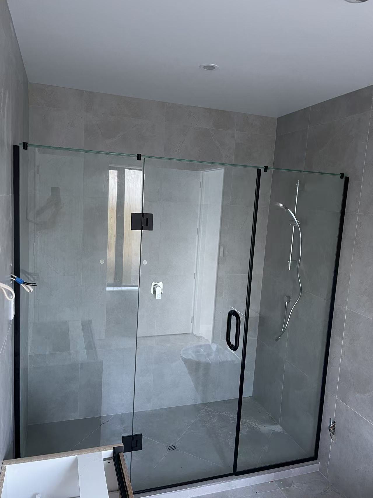 Wide frameless shower enclosure with black framing and hardware