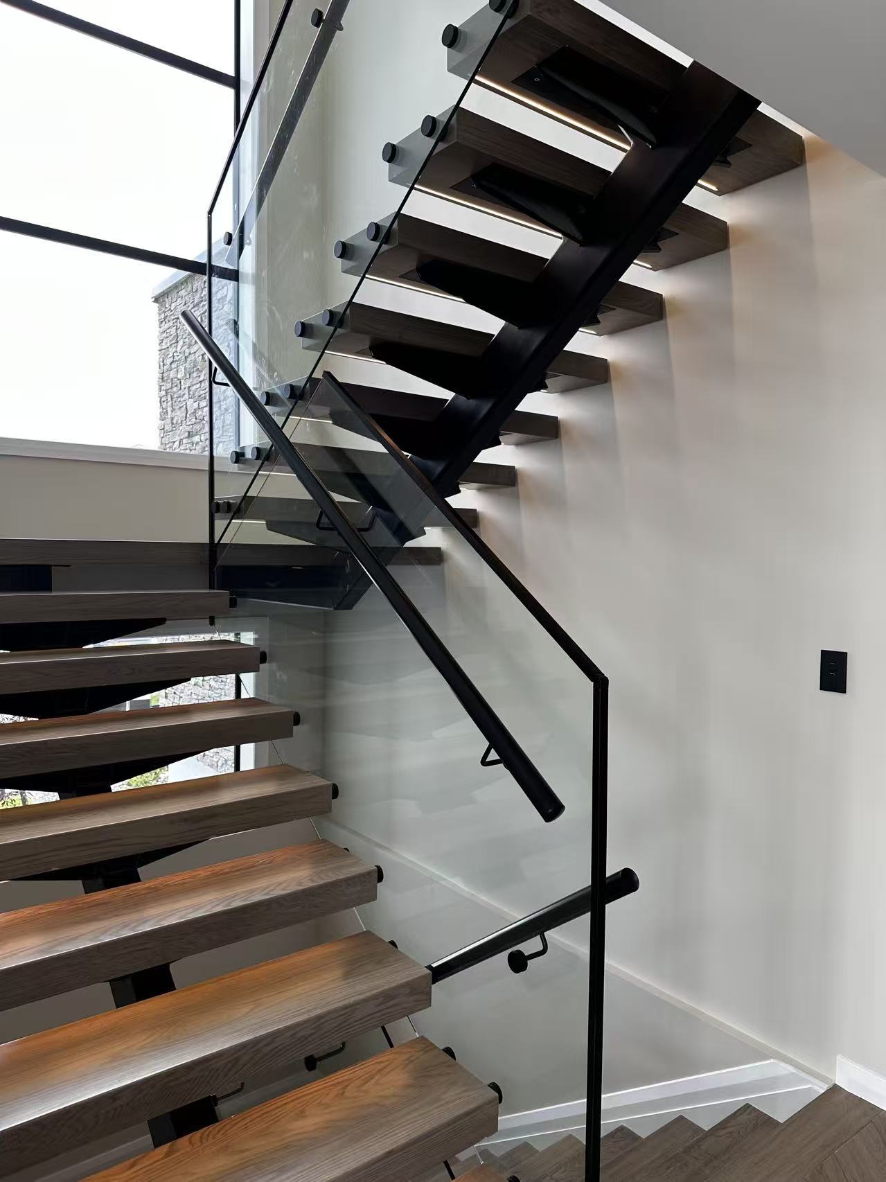 Floating timber stair with clear glass and black handrail